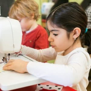 little girl sewing in sewing class
